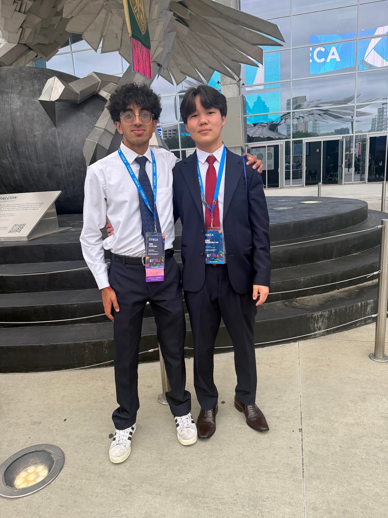 Eric in a navy suit and red tie with a teammate outside the DECA International Career Development Conference.