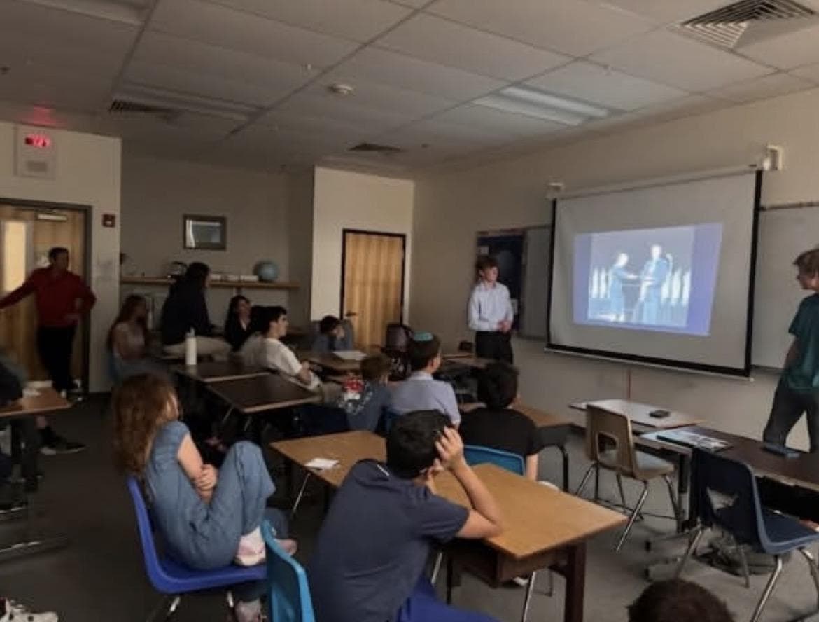 A classroom at Denver Jewish Day School during Empower Debate mentoring, with a debate round projected on the screen.